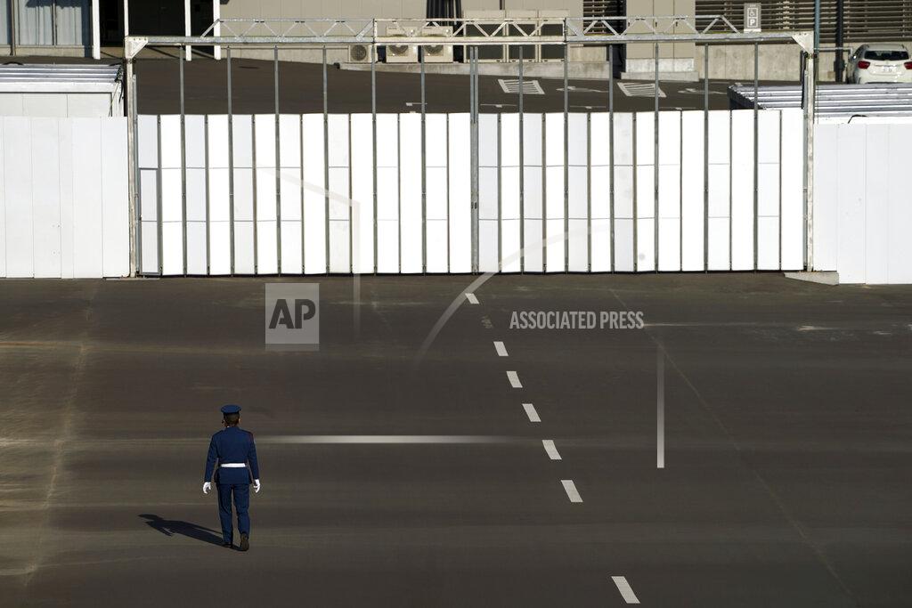 Eugene Hoshiko A security guard walks at parking lot of Ariake Gymnastics Centre, one of the venues of Tokyo 2020 Olympic and Paralympic games, in Tokyo Thursday, Jan. 21, 2021. The postponed Tokyo Olympics are to open in just six months. Local organizers and the International Olympic Committee say they will go ahead on July 23. But it’s still unclear how this will happen with virus cases surging in Tokyo and elsewhere around the globe. (AP Photo/Eugene Hoshiko)