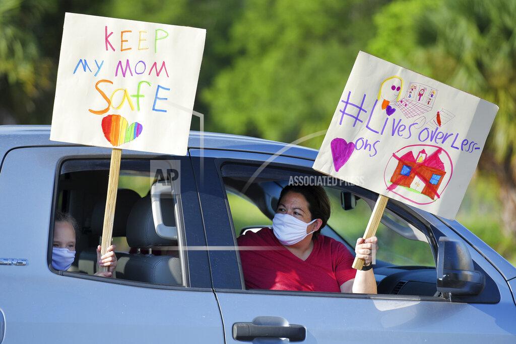 Story Collins, 9 and her mother Heather Correia show their support for teachers after arriving at the Duval County School Board building, Tuesday, July 14, 2020 in Jacksonville, Fla. Duval County teachers and their supporters gathered in a parking lot before they drove to the Duval County School Board Building and protest plans of starting the upcoming school year with the rate of COVID-19 infections hitting record rates in Jacksonville. (Bob Self/The Florida Times-Union via AP)
