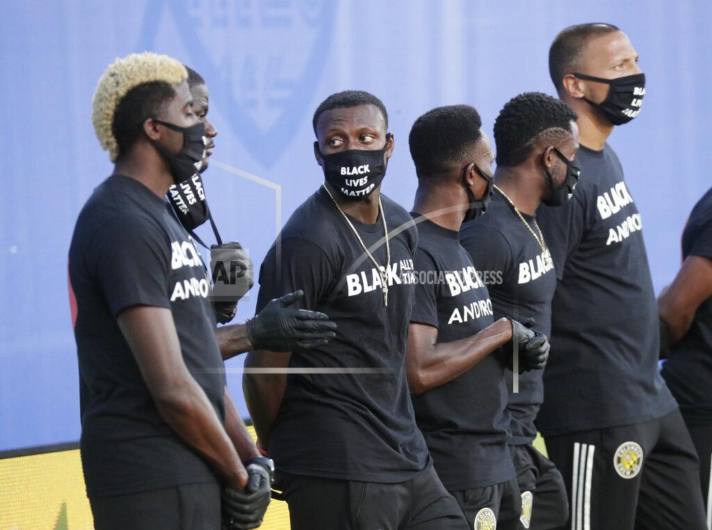 John Raoux Members of the Columbus Crew, wearing shirts and masks with messages about race, stand on the field before an MLS soccer match Wednesday, July 8, 2020, in Kissimmee, Fla. (AP Photo/John Raoux)