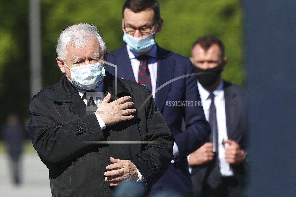 Poland's ruling party leader Jaroslaw Kaczynski, left, and Prime Minister Mateusz Morawiecki, center, wearing masks, pray at the monument to the late President Lech Kaczynski, the party leader's twin, killed with 95 others in a plane crash April 10, 2010 in Russia, in Warsaw, Poland Sunday, May 10, 2020. Poland was to hold presidential election Sunday but the anti-coronavirus lockdown and political infighting made it impossible and there is no voting. (AP Photo/Czarek Sokolowski)