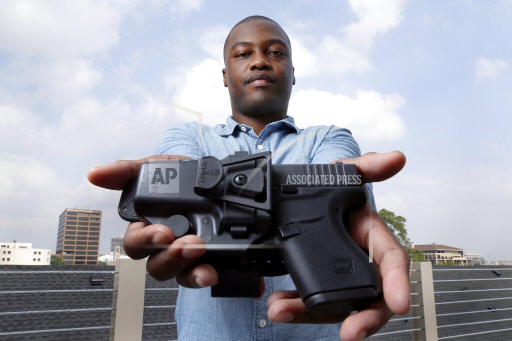 Michael Wyke Charles Blain, a new gun owner, poses with his holstered 9mm Glock 43 handgun, Monday, May 3, 2021, on the parking garage of his apartment complex in Houston. Blain also owns a shotgun and is currently completing his concealed carry license requirements to carry the handgun. Blain, who describes himself as a conservative, says "pandemic-related unemployment crime" and repeated calls over the past year to release hundreds of jail inmates because of soaring COVID-19 infections pushed him to buy. (AP Photo/Michael Wyke)