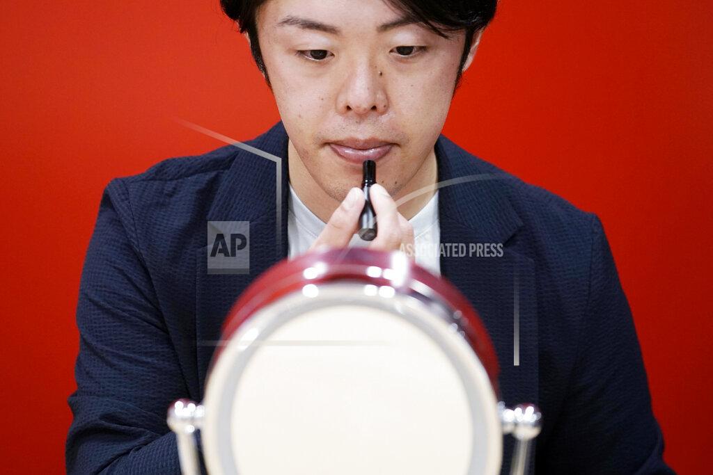 Eugene Hoshiko Naruhiko Ito, assistant brand manager of Brand Shiseido Group, demonstrates the brand's latest lip balm for men in Tokyo Thursday, April 15, 2021. A large personal care company, Shiseido, says one of its male makeup lines has seen double-digit growth during the coronavirus pandemic. Company officials give a similar reason: Men, confronted with the sight of their faces repeatedly during online meetings, want to improve what they see. (AP Photo/Eugene Hoshiko)