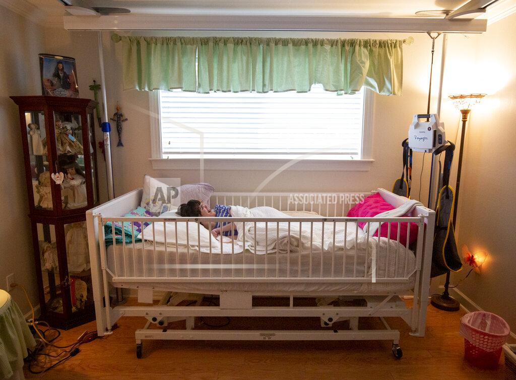 Sophia Germer Lauren, the daughter of Sue Roesky who has cerebral palsy and is non-verbal, lies in a specialized and necessary bed that took Sue about a year to get approved by Medicaid and Durable Medical Equipment, at their home in Metairie, La., Friday, Sept. 17, 2021. (Sophia Germer/The Times-Picayune/The New Orleans Advocate via AP)