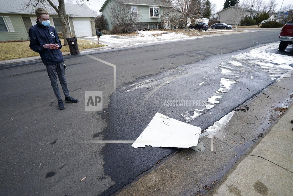 David Zalubowski A man looks over debris that fell off a plane as it shed parts over a neighborhood in Broomfield, Colo., Saturday, Feb. 20, 2021. The plane was making an emergency landing at nearby Denver International Airport. (AP Photo/David Zalubowski)