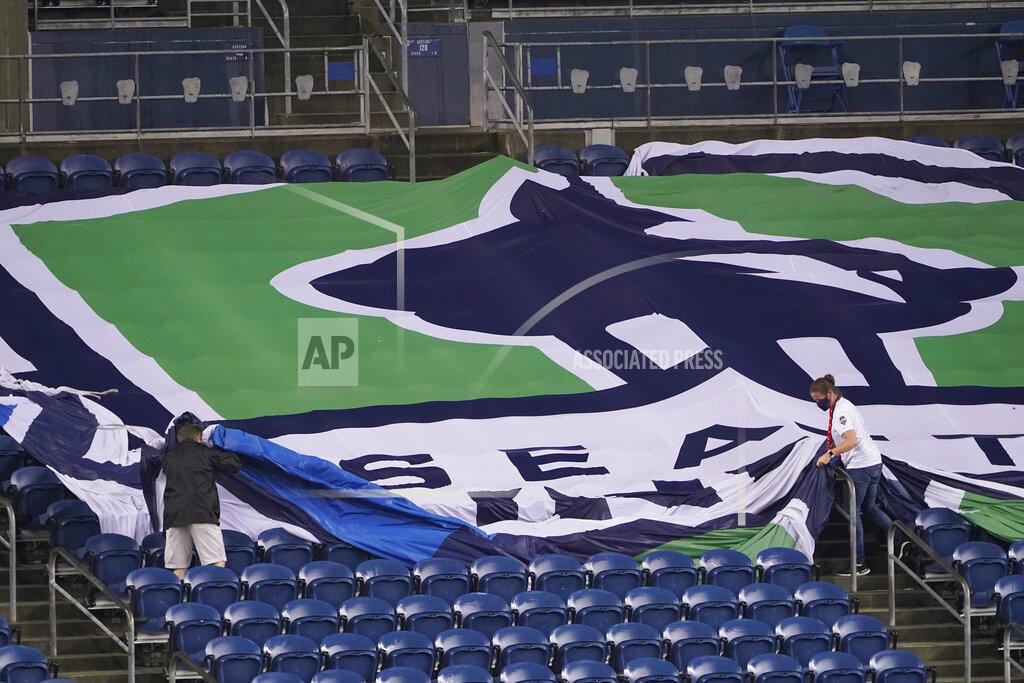 Ted S. Warren Workers remove a Seattle Sounders banner from the stands at CenturyLink Field following an MLS soccer match between the Sounders and Los Angeles FC, Friday, Sept. 18, 2020, in Seattle. The stadium is being prepared for Sunday's NFL football game between the Seattle Seahawks and the New England Patriots. (AP Photo/Ted S. Warren)