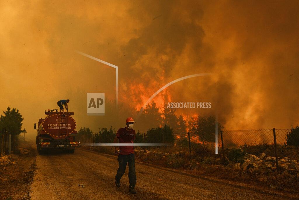 Uncredited A man down a road in the fire-devastating Sirtkoy village, near Manavgat, Antalya, Turkey, Sunday, Aug. 1, 2021. More than 100 wildfires have been brought under control in Turkey, according to officials. The forestry minister tweeted that five fires are continuing in the tourist destinations of Antalya and Mugla. (AP Photo)