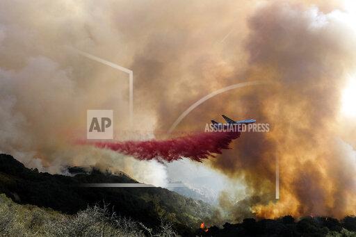 An air tanker drops retardant on a wildfire Wednesday, Oct. 13, 2021, in Goleta, Calif. A wildfire raging through Southern California coastal mountains threatened ranches and rural homes and kept a major highway shut down Wednesday as the fire-scarred state faced a new round of dry winds that raise risk of flames. The Alisal Fire covered more than 22 square miles (57 square kilometers) in the Santa Ynez Mountains west of Santa Barbara. (AP Photo/Ringo H.W. Chiu)