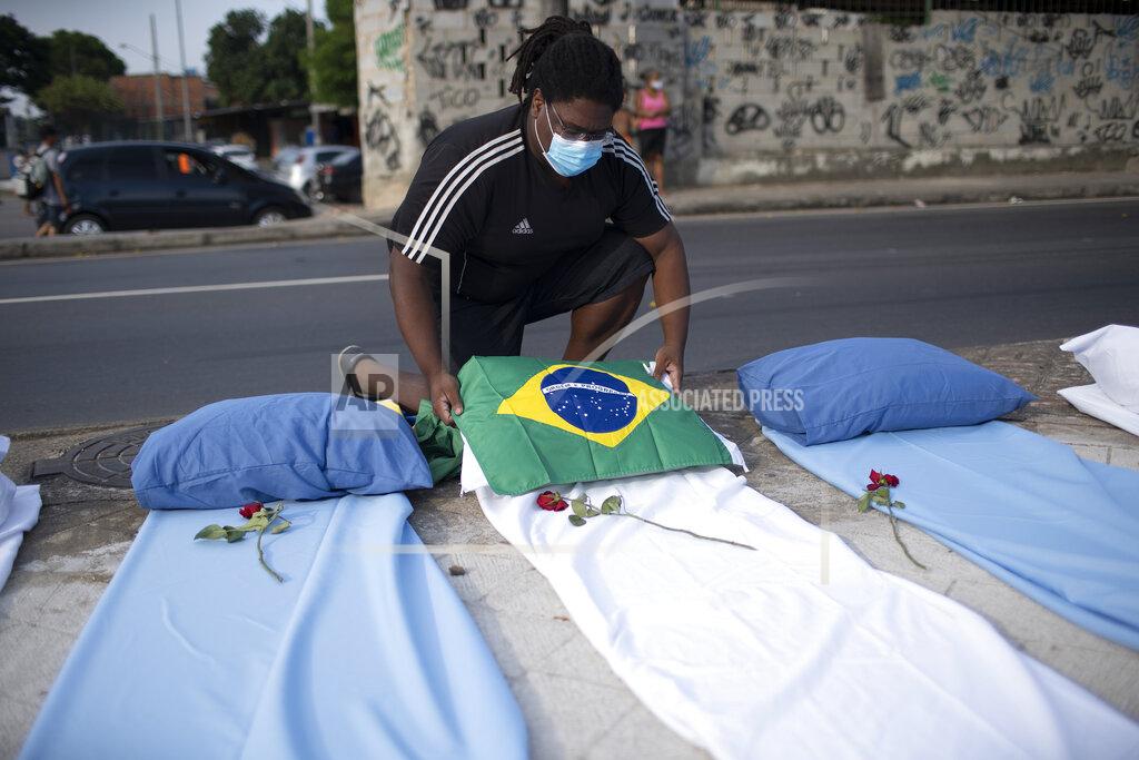 Silvia Izquierdo A demonstrator places a Brazil national flag on a mattress symbolizing COVID-19 victims, during a protest against the Government's handling of the COVID-19 pandemic, organized by the Rio de Paz NGO, in front of the Ronaldo Gazolla hospital in Rio de Janeiro, Brazil, Wednesday, March 24, 2021. (AP Photo/Silvia Izquierdo)