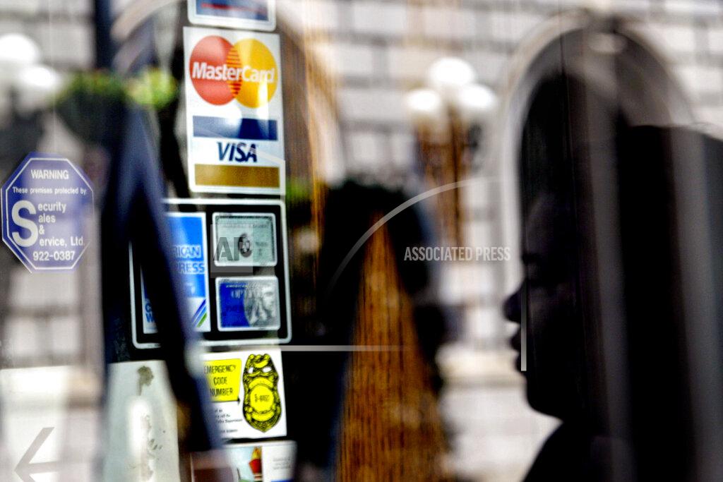 FILE - In this July 18, 2012, file photo, credit logos are displayed on a downtown storefront as a pedestrian passes in Atlanta. U.S. consumer borrowing rose by a solid 3.6% in July, the second monthly gain after the coronavirus pandemic had sent consumer borrowing down sharply in the previous three months, the Federal Reserve reported Tuesday, Sept. 8, 2020. (AP Photo/Ashley Hopkinson, File)