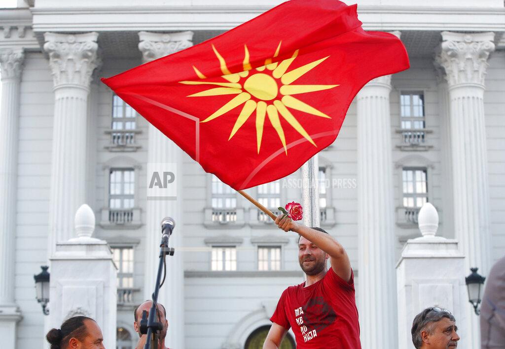 Boris Grdanoski A protester waves the old national flag during a protest in front of the government building in Skopje, North Macedonia, on Saturday, July 2, 2022. Tens of thousands of people have gathered late on Saturday in North Macedonia's capital Skopje to protest the latest French presidency proposal on solving bilateral disputes with Bulgaria that gave directions for small Balkan country to open membership talks with the European Union. (AP Photo/Boris Grdanoski)