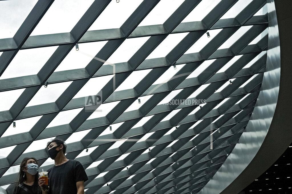 Andy Wong A couple wearing face masks to help curb the spread of the coronavirus walk by a structure of a shopping mall in Beijing, Sunday, June 6, 2021. (AP Photo/Andy Wong)