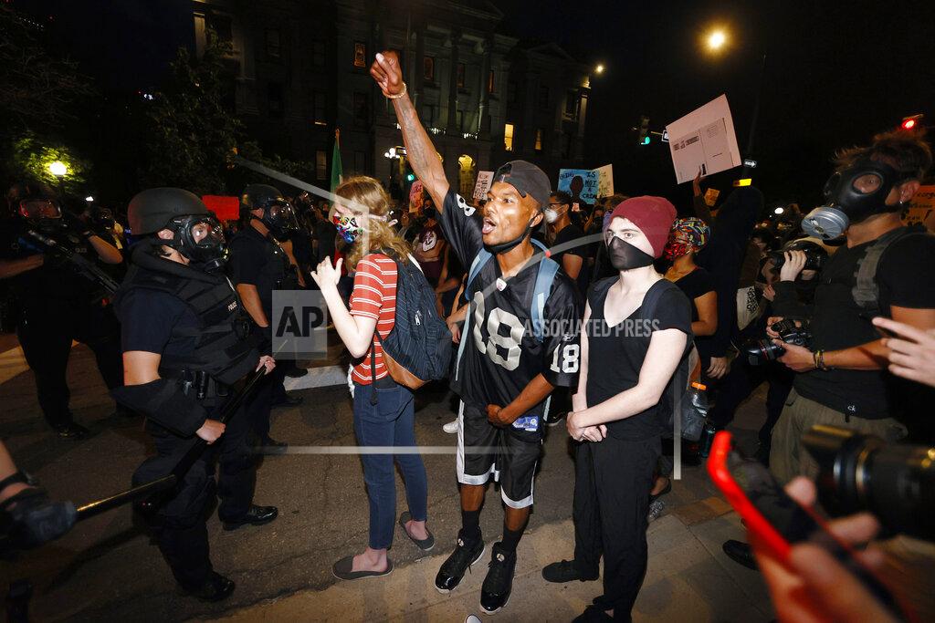 David Zalubowski Denver police stand in front of protesters outside the State Capitol during a demonstration over the Monday death of George Floyd, a handcuffed black man in Minneapolis police custody, Thursday, May 28, 2020, in Denver. (AP Photo/David Zalubowski)