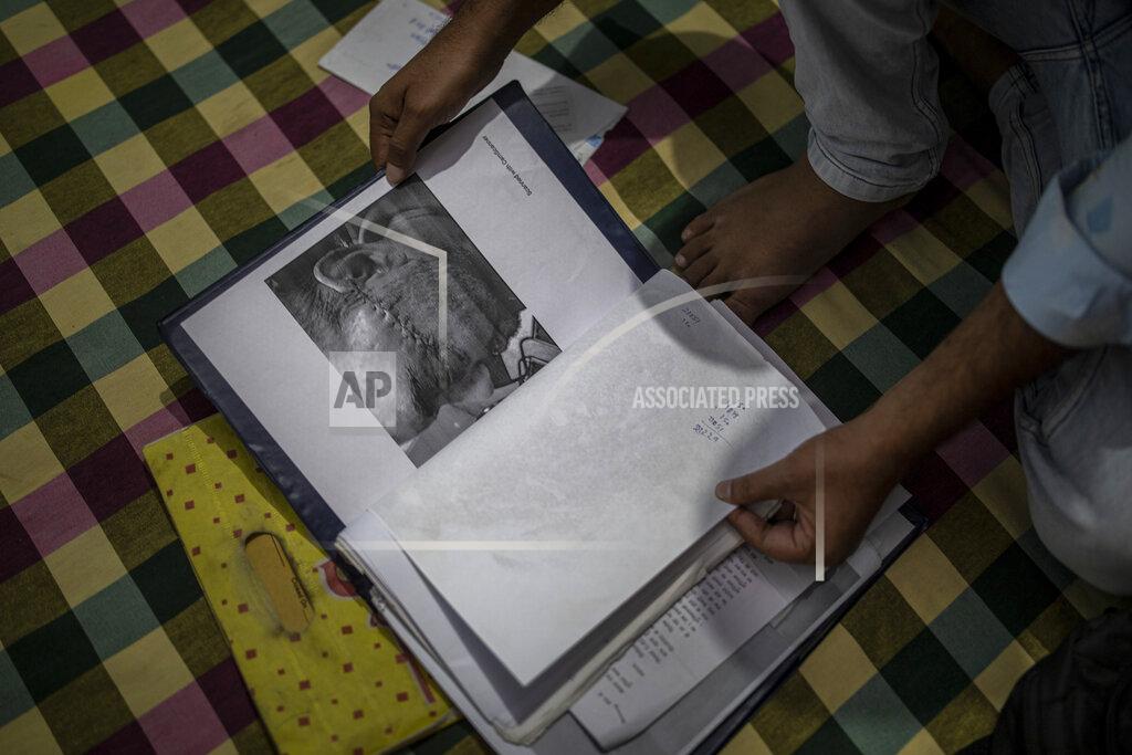 Altaf Qadri Muhammad Nasir Khan, who was shot by a Hindu mob during the February 2020 communal riots, sifts through his legal and medical files inside his home in North Ghonda, one of the worst riot affected neighborhood, in New Delhi, India, Friday, Feb. 19, 2021. As the first anniversary of bloody communal riots that convulsed the Indian capital approaches, Muslim victims are still shaken and struggling to make sense of their struggle to seek justice. (AP Photo/Altaf Qadri)
