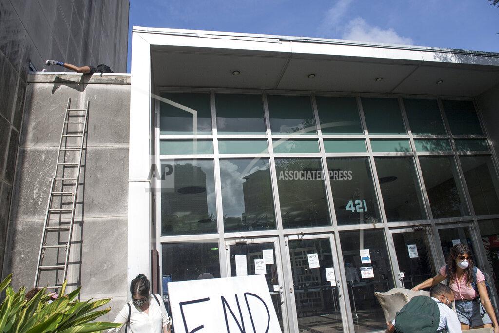 Chris Granger A protester, top left, climbs a ladder in order to hang a sign from the roof of First City Court near New Orleans City Hall during the Renters Rights Assembly protest on Thursday, July 30, 2020. (Chris Granger/The Advocate via AP)