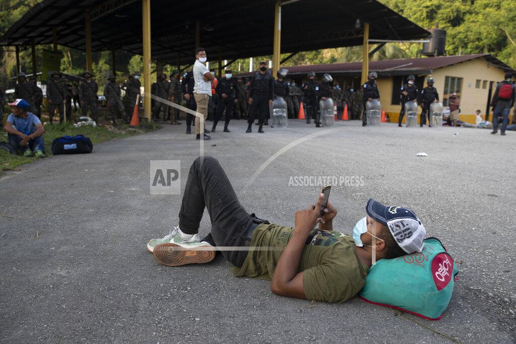 Moises Castillo An Honduran migrant rests in front of a road block set by security forces in Poptun, Guatemala, Friday, Oct. 2, 2020. Guatemala vowed to detain and return members of a caravan of hundreds of migrants that set out from neighboring Honduras in hopes of reaching the United States, saying they represent a health threat amid the coronavirus pandemic. (AP Photo/Moises Castillo)