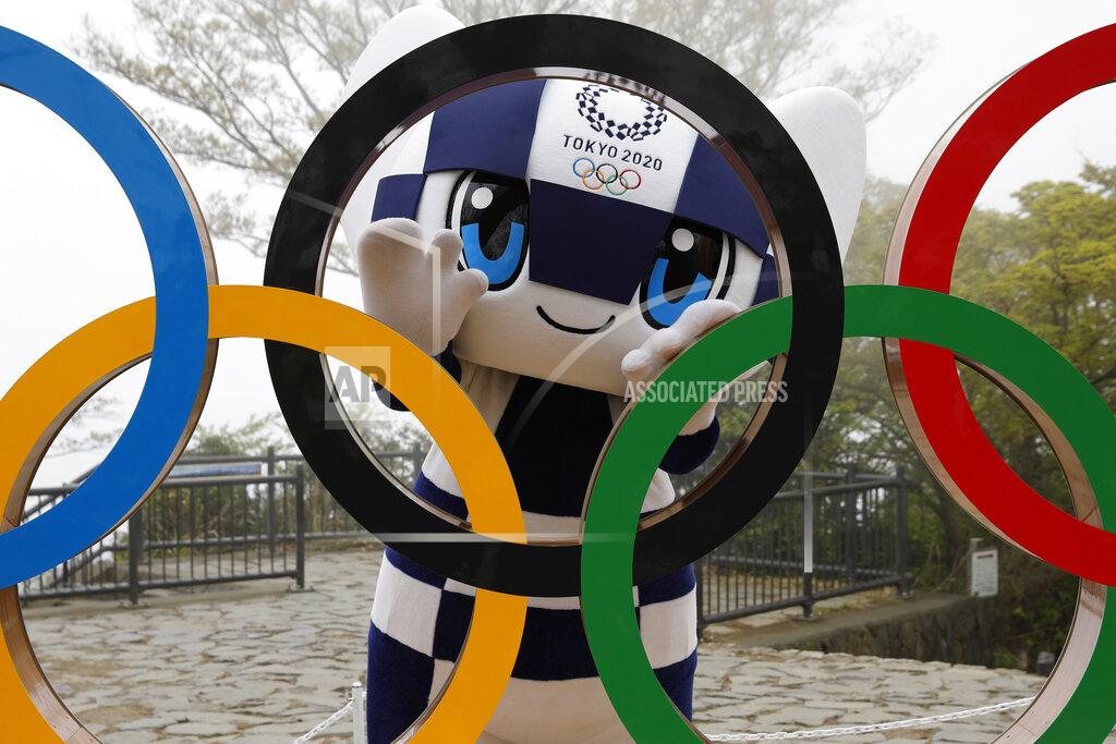 FILE - In this April 14, 2021, file photo, Tokyo 2020 Olympic Games mascot Miraitowa poses with a display of Olympic Symbol after an unveiling ceremony of the symbol on Mt. Takao in Hachioji, west of Tokyo to mark 100 days before the start of the Olympic Games. Japan is set to raise the coronavirus alert level in Tokyo’s three neighboring prefectures and a forth area in central Japan to allow tougher measures as a more contagious coronavirus variant spreads and doubts are growing whether the Olympics can go ahead. (Kim Kyung-Hoon/Pool Photo via AP)