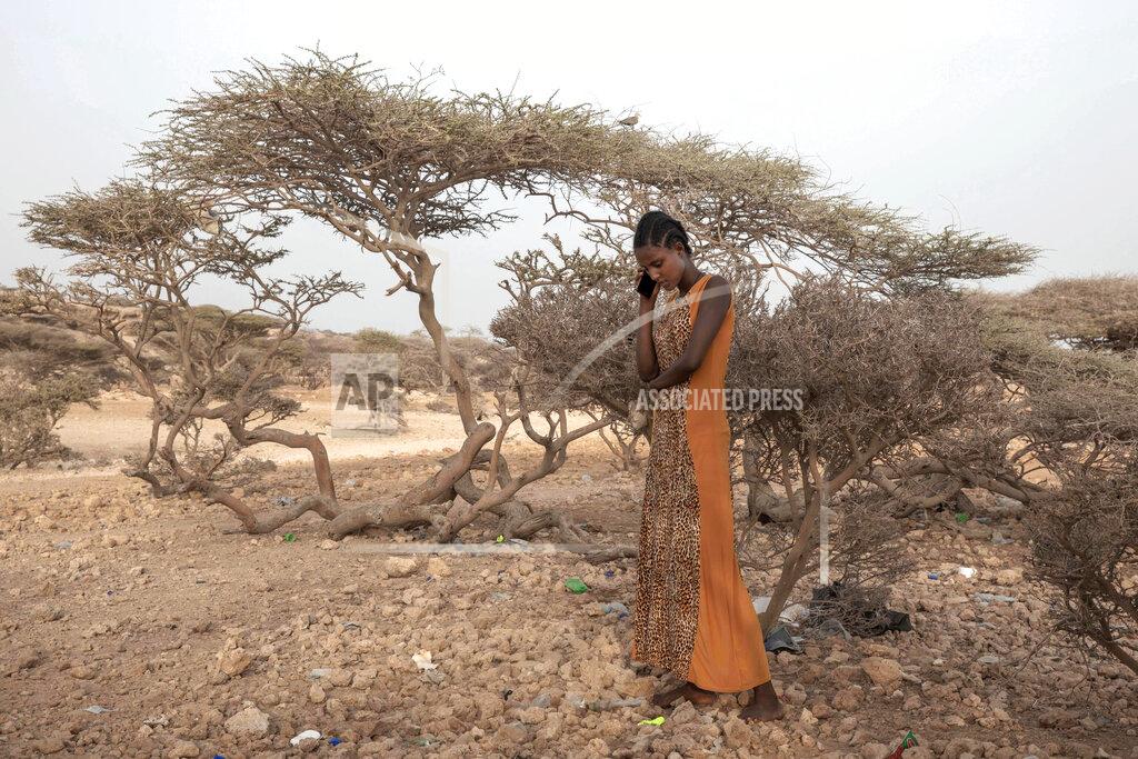 Nariman El-Mofty FILE - In this July 15, 2019 file photo, an Ethiopian Tigray migrant, makes a phone call to her mother in Ethiopia, as she takes shelter under trees at the last stop of her journey before leaving by boat to Yemen in the evening, in Obock, Djibouti. Ethiopia's Tigray region was among the leading sources of new flows of refugees and internally displaced people in 2020, according to Global Trends report released on Friday June 18, 2021, by the United Nations refugee agency UNHCR. (AP Photo/Nariman El-Mofty, FILE)