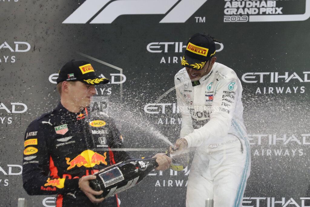 Hassan Ammar Mercedes driver Lewis Hamilton of Britain, right, celebrates on the podium after wining the Emirates Formula One Grand Prix, with second place Red Bull driver Max Verstappen of the Netherland's at the Yas Marina racetrack in Abu Dhabi, United Arab Emirates, Sunday, Dec.1, 2019. (AP Photo/Hassan Ammar)