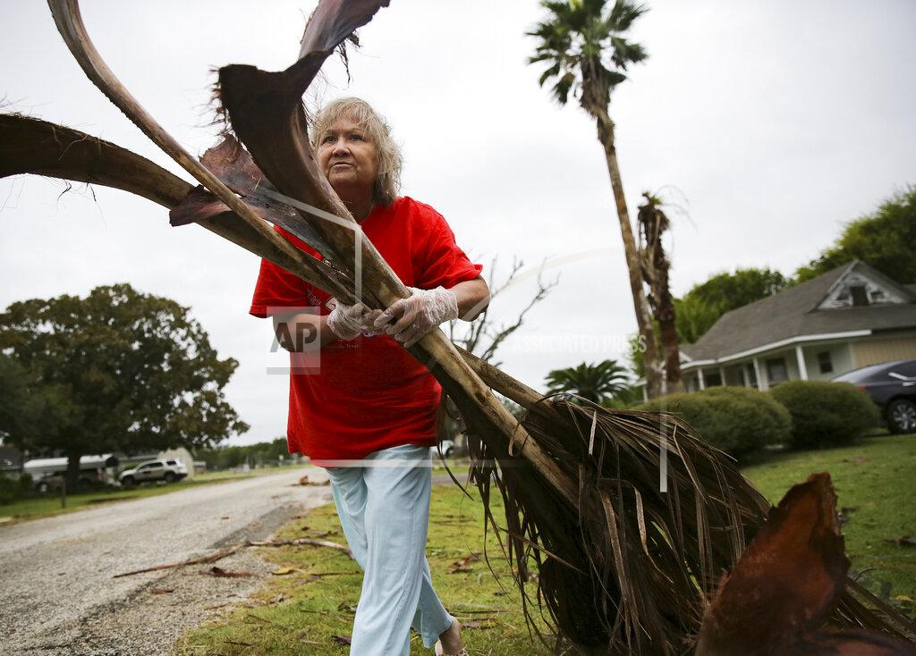 Elizabeth Conley Alfa Alamia cleans up her brother's yard in Palacios, Texas following Hurricane Nicholas on Tuesday, Sept. 14, 2021. Alamia has lived in Palacios since she was 12. (Elizabeth Conley/Houston Chronicle via AP)