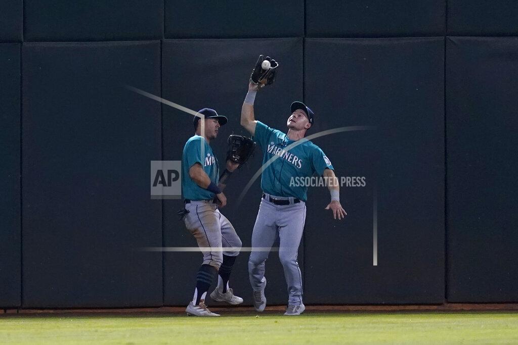 Jeff Chiu Seattle Mariners center fielder Jarred Kelenic, right, catches a flyout hit by Oakland Athletics' Yan Gomes next to left fielder Dylan Moore during the fourth inning of a baseball game in Oakland, Calif., Monday, Sept. 20, 2021. (AP Photo/Jeff Chiu)