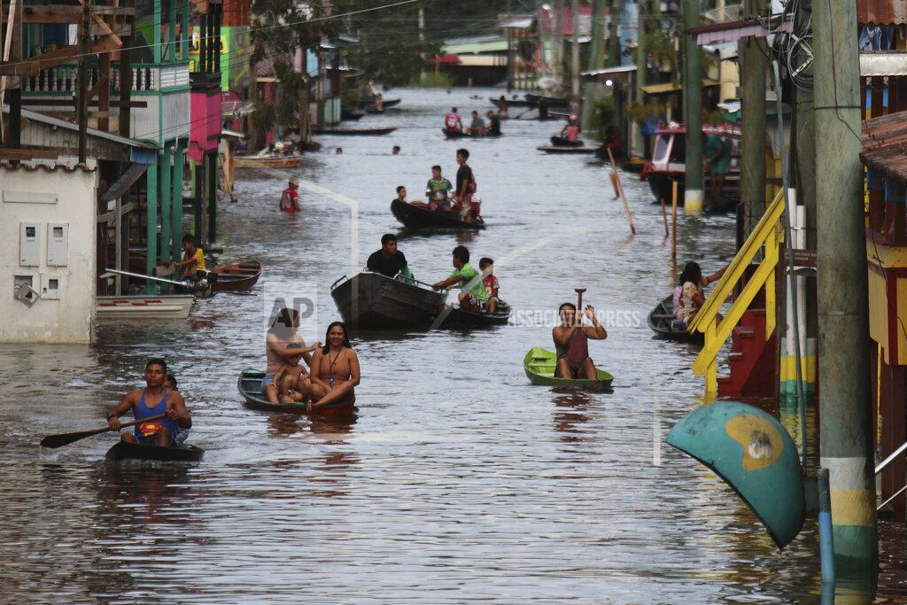Edmar Barros Residents navigate a flooded street in Anama, Amazonas state, Brazil, Thursday, May 13, 2021. (AP Photo/Edmar Barros)