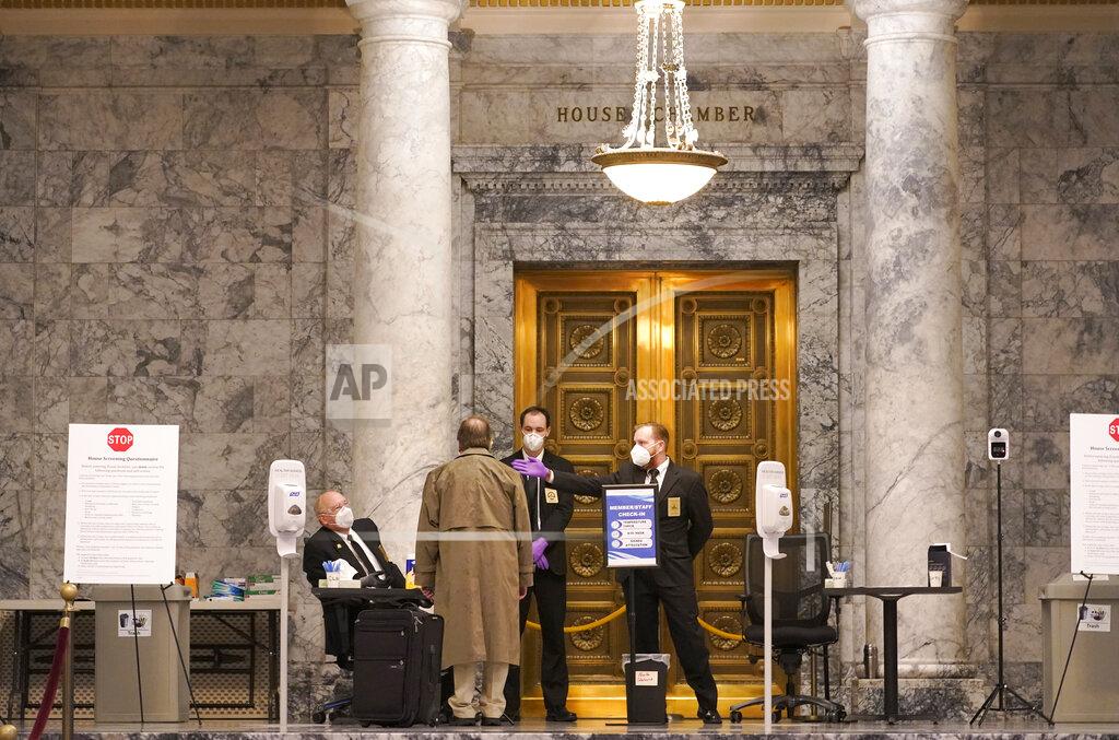 Ted S. Warren FILE - In this Jan. 11, 2021 file photo, staff members perform health checks at the entrance to the House Chambers on the first day of the 2021 legislative session at the Capitol in Olympia, Wash. The 2021 session of the Washington Legislature ended Sunday, April 25 and lawmakers had no shortage of weighty topics to consider while having to conduct their work amid a pandemic that meant most meetings and votes were conducted remotely. The Capitol building was also closed to the public since last year due to the COVID-19 pandemic, and was surrounded by security fencing and national guard members at times due to fears of protests. (AP Photo/Ted S. Warren, File)