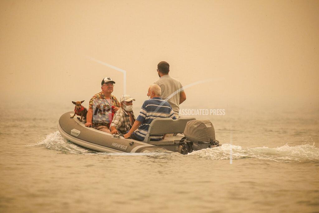 Emre Tazegul Tourists are evacuated from smoke-engulfed Mazi area as wildfires rolled down the hill toward the seashore, in Bodrum, Mugla, Turkey, Sunday, Aug. 1, 2021. More than 100 wildfires have been brought under control in Turkey, according to officials. The forestry minister tweeted that five fires are continuing in the tourist destinations of Antalya and Mugla. (AP Photo/Emre Tazegul)