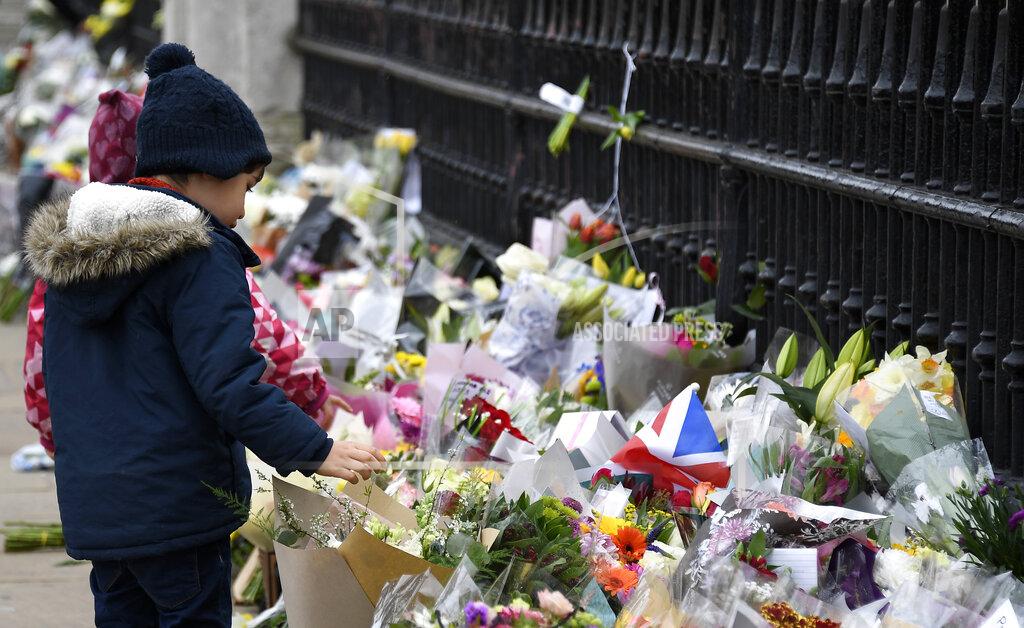 Alberto Pezzali A child looks at flowers left outside the gates of Buckingham Palace in London, a day after the death of Britain's Prince Philip, Saturday, April 10, 2021. Britain's Prince Philip, the irascible and tough-minded husband of Queen Elizabeth II who spent more than seven decades supporting his wife in a role that mostly defined his life, died on Friday. (AP Photo/Alberto Pezzali)