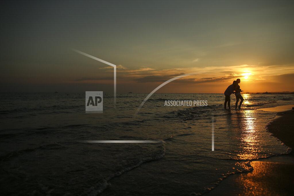 Emrah Gurel Tourists visit the beach of Antalya, southern Turkey, as the sun sets , on Sunday, June 20, 2021. Hotels in Turkey's Antalya region, a destination beloved by holidaymakers, are preparing to finally resume operations as they expect the return of international tourists after months of setbacks caused by the pandemic that halted travel. (AP Photo/Emrah Gurel)