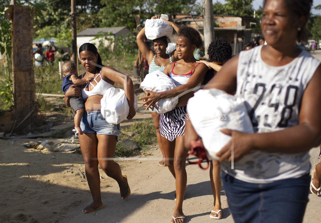 Silvia Izquierdo Women carry home bags of donated food, distributed by the the Covid Without Hunger organization in the Jardim Gramacho slum of Rio de Janeiro, Brazil, Saturday, May 22, 2021. Food insecurity for people with informal jobs is quadruple that of salaried employees, according to Tereza Campello, a former minister of social development. (AP Photo/Silvia Izquierdo)