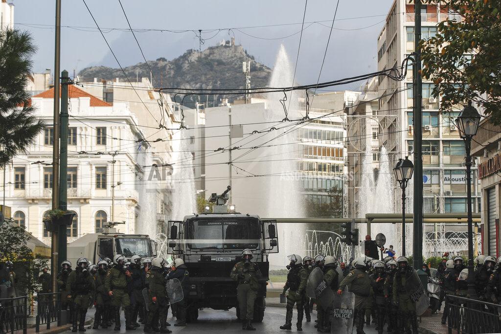 Riot police walk next a water cannon vehicle kin central Omonoia square central Athens, on Tuesday, Nov. 17, 2020. Police have detained several people and fired tear gas during scuffles in Athens as hundreds of protesters defied a ban on gatherings of more than three people to mark the anniversary of the crushing of a 1973 student uprising against the military junta then ruling Greece. (AP Photo/Thanassis Stavrakis)
