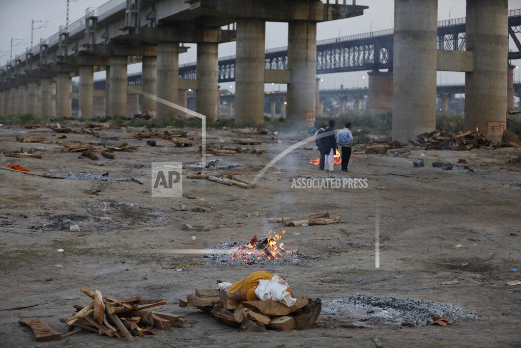 Rajesh Kumar Singh Relatives stand near the funeral pyre of their loved one who died due to COVID-19 at a cremation ground in Prayagraj, India, Saturday, May 8, 2021. (AP Photo/Rajesh Kumar Singh)