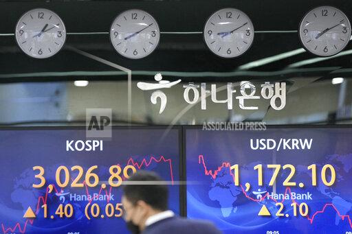 A currency trader walks by screens showing the Korea Composite Stock Price Index (KOSPI), left, and the foreign exchange rate between U.S. dollar and South Korean won at a foreign exchange dealing room in Seoul, South Korea, Thursday, Oct. 28, 2021. Asian shares fell Thursday after a retreat on Wall Street as banks and health care companies pulled the S&P 500 and the Dow Jones Industrial Average back from their latest record highs. (AP Photo/Lee Jin-man)