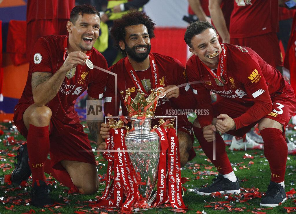 Phil Noble Liverpool's Mohamed Salah, ceter, and Liverpool's Xherdan Shaqiri, right, and Liverpool's Dejan Lovren pose with the English Premier League trophy following its presentation after the English Premier League soccer match between Liverpool and Chelsea at Anfield Stadium in Liverpool, England, Wednesday, July 22, 2020. Liverpool are champions of the EPL for the season 2019-2020. The trophy is presented at the teams last home game of the season. Liverpool won the match against Chelsea 5-3. (Phil Noble/Pool via AP)