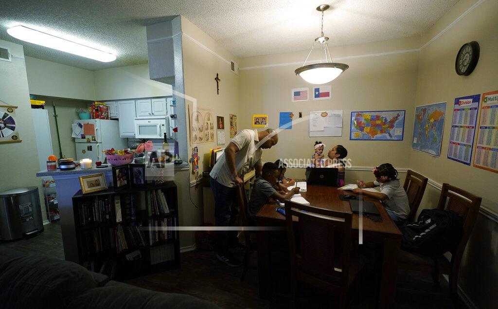 Eric Gay Arlena Brown, center, holds her youngest child, Lucy, 9 months, as she and husband, Robert, left, lead their other children, from left, Jacoby, 11; Felicity, 9, and Riley, 10, through math practice at their home in Austin, Texas, Tuesday, July 13, 2021. “I didn’t want my kids to become a statistic and not meet their full potential,” said Robert, a former teacher who now does consulting. “And we wanted them to have very solid understanding of their faith.” (AP Photo/Eric Gay)