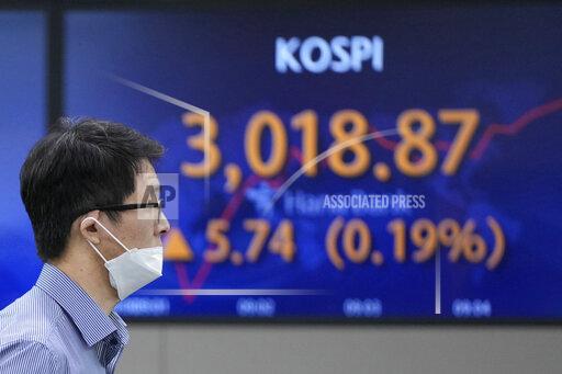 A currency trader walks near a screen showing the Korea Composite Stock Price Index (KOSPI) at a foreign exchange dealing room in Seoul, South Korea, Thursday, Oct. 21, 2021. Shares are mixed in Asia after major Chinese property developer Evergrande said a plan to sell its property management arm to a smaller rival had fallen through. (AP Photo/Lee Jin-man)