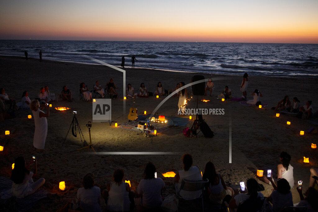 Maya Alleruzzo Women take part in a Tashlich ceremony, where they wrote down things they want to release before casting them into a fire, on the beach in Tel Aviv, Israel, Tuesday, Sept. 14, 2021. Tashlich, which means 'to cast away' in Hebrew, is the practice by which Jews go to a large flowing body of water and symbolically 'throw away' their sins by throwing a piece of bread, or similar food, into the water before the Jewish holiday of Yom Kippur, the holiest day in the Jewish year which starts at sundown Wednesday. (AP Photo/Maya Alleruzzo)