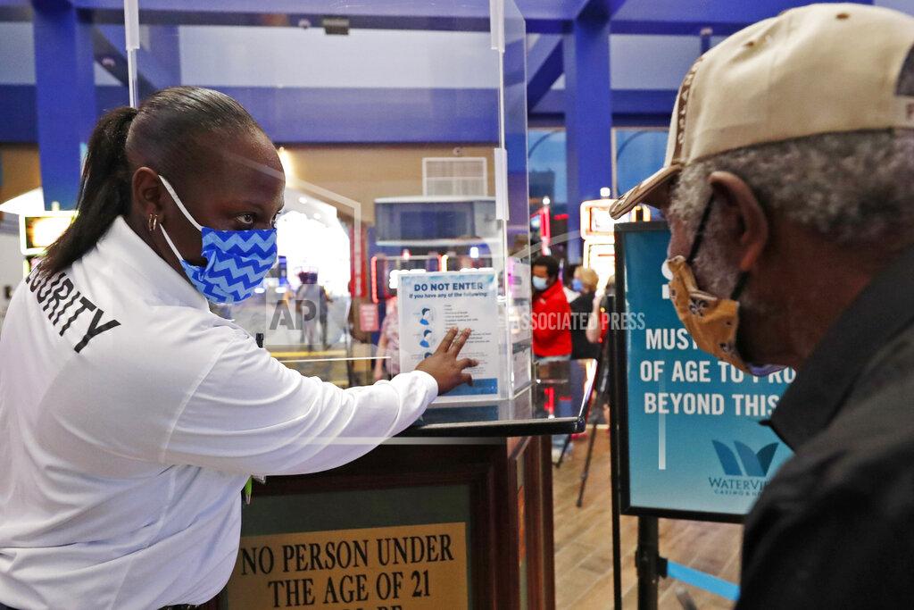 Lead Security Officer Tiffany White, left, asks precautionary health status questions of a patron entering WaterView Casino and Hotel in Vicksburg, Miss., Thursday, May 21, 2020, for a morning of gaming, following a two-month shutdown due to coronavirus. Casinos statewide are allowed to reopen Thursday, amid enhanced restrictions to keep customers and employees safe. (AP Photo/Rogelio V. Solis)