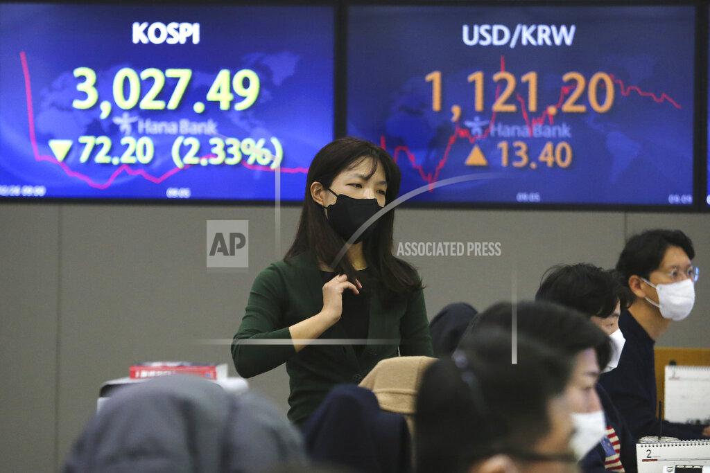 Ahn Young-Joon A currency trader walks near screens showing the Korea Composite Stock Price Index (KOSPI), left, and the foreign exchange rate between U.S. dollar and South Korean won at the foreign exchange dealing room of the KEB Hana Bank headquarters in Seoul, South Korea, Friday, Feb. 26, 2021. Asian shares skidded Friday after rising bond yields triggered a broad sell-off on Wall Street that erased the markets gain for the week and handed the Nasdaq composite index its steepest loss since October. (AP Photo/Ahn Young-joon)