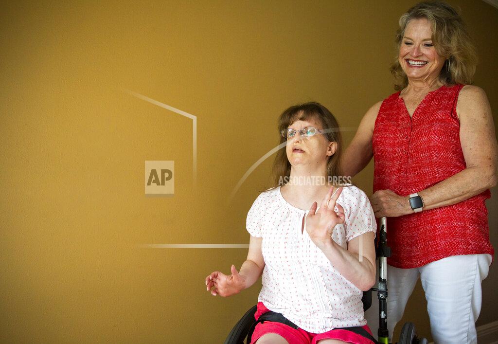 Sophia Germer Jen Dwyer, a 44-year-old woman with intellectual and developmental disabilities, dances and sings along with Mariah Carey Christmas carols next to her mother, Kathy Dwyer, at their home in Metairie, La., Friday, Sept. 17, 2021. (Sophia Germer/The Times-Picayune/The New Orleans Advocate via AP)