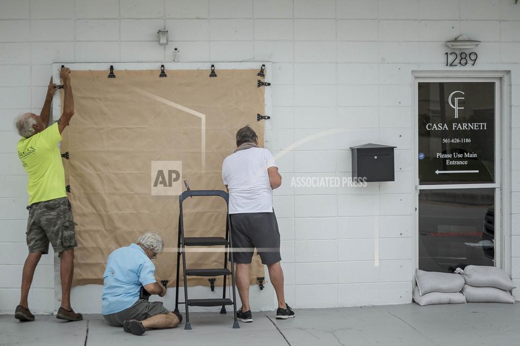 Thomas Cordy People install hurricane fabric on windows openings at Casa Farneti on in Riviera Beach, Fla., as Palm Beach County readies for Hurricane Isaias on Saturday, Aug. 1, 2020. Isaias snapped trees and knocked out power as it blew through the Bahamas on Saturday and churned toward the Florida coast, where it is threatening to complicate efforts to contain the coronavirus in a hot spot. (Thomas Cordy/The Palm Beach Post via AP)