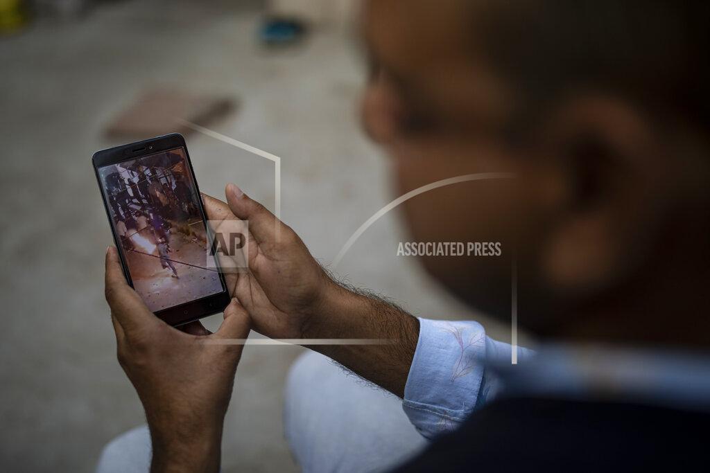 Altaf Qadri Muhammad Nasir Khan, who was shot by a Hindu mob during the February 2020 communal riots, watches a video showing a Hindu mob throwing petrol bomb towards a Muslim house in North Ghonda, one of the worst riot affected neighborhood, in New Delhi, India, Friday, Feb. 19, 2021. As the first anniversary of bloody communal riots that convulsed the Indian capital approaches, Muslim victims are still shaken and struggling to make sense of their struggle to seek justice. (AP Photo/Altaf Qadri)