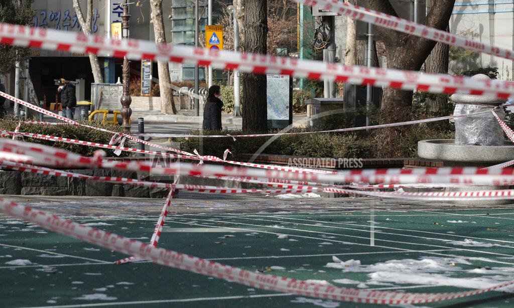 Lee Jin-Man People wearing face masks walk near a park, which is taped for the social distancing measures and a precaution against the coronavirus in Seoul, South Korea, Thursday, Jan. 14, 2021. (AP Photo/Lee Jin-man)