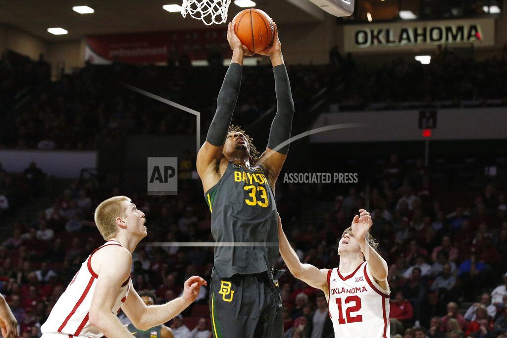 Sue Ogrocki Baylor forward Freddie Gillespie (33) shoots between Oklahoma forward Brady Manek, left, and guard Austin Reaves during the first half of an NCAA college basketball game in Norman, Okla., Tuesday, Feb. 18, 2020. (AP Photo/Sue Ogrocki)