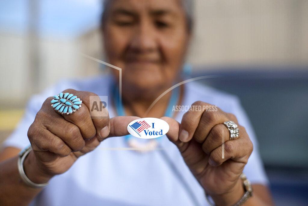 Cayla Nimmo FILE - In this Aug. 28, 2018, file photo, Mildred James of Sanders, Arizona, shows off her "I Voted" sticker as she awaits election results in Window Rock, Arizona, on the Navajo Nation. The tribe says bills recently signed into Arizona law would make voting more difficult than it already is on the vast reservation. (AP Photo/Cayla Nimmo, File)