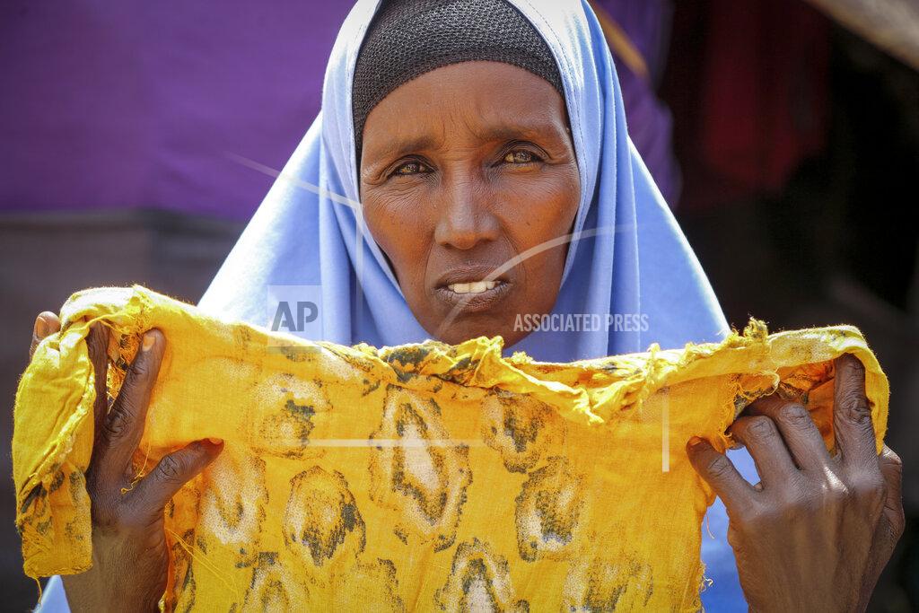 Farah Abdi Warsameh Hawa Osman Bilal shows the clothes of her daughter Ifrah, who like many vulnerable Somalis died during the difficult journey from drought-stricken areas, outside her makeshift tent at a camp for the displaced on the outskirts of Mogadishu, Somalia Thursday, June 30, 2022. The war in Ukraine has abruptly drawn millions of dollars away from longer-running humanitarian crises and Somalia is perhaps the most vulnerable as thousands die of hunger amid the driest drought in decades. (AP Photo/Farah Abdi Warsameh)