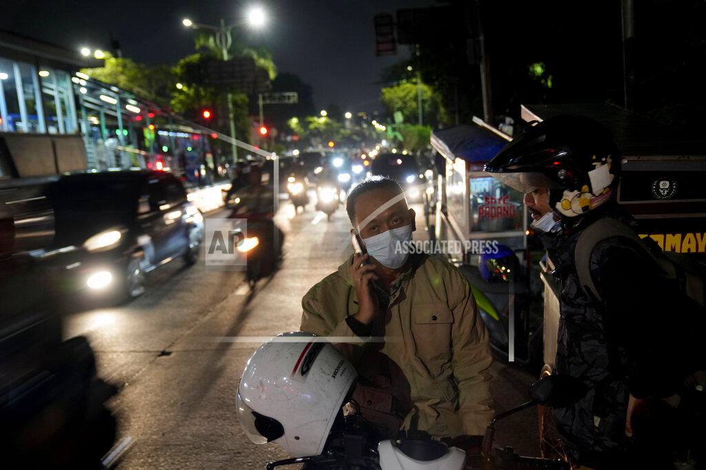 Dita Alangkara A motorist wearing a mask talks on his mobile phone in Jakarta, Indonesia, Tuesday, May 17, 2022. Indonesia will lift its outdoor mask mandate because its COVID-19 outbreak appears to be waning, President Joko Widodo said Tuesday. (AP Photo/Dita Alangkara)