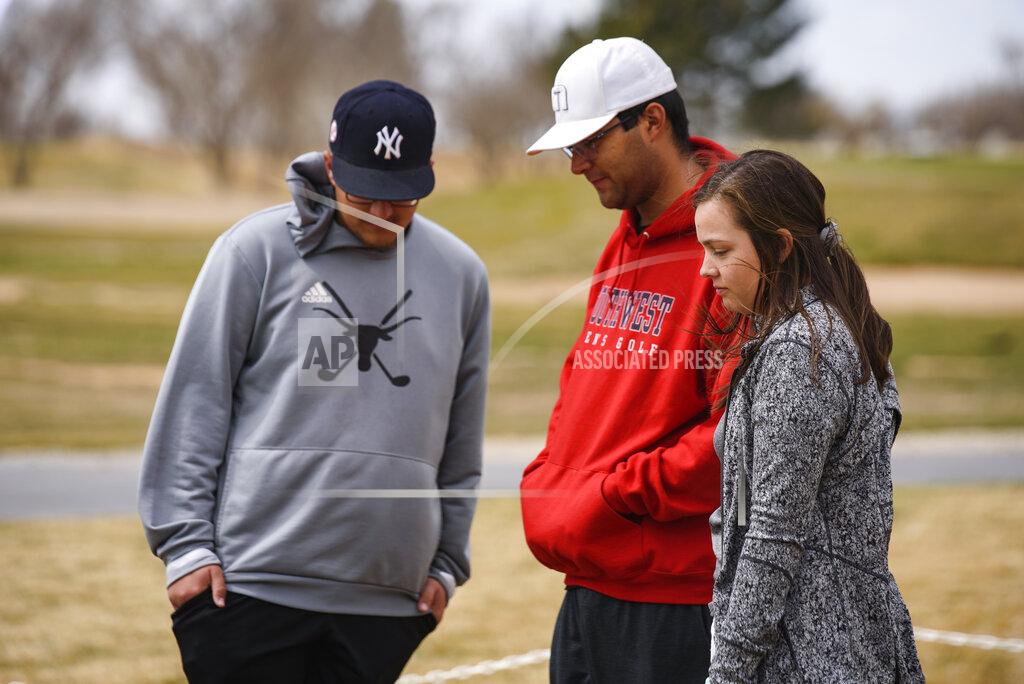 Eli Hartman University of the Southwest golf players from left, Phillip Lopez, Jonny Flores and Halie Cruz visit the site of a memorial erected for the victims of the USW golf teams car wreck Thursday, March 17, 2022 at the Rockwind Community Links in Hobbs, N.M. (Eli Hartman/Odessa American via AP)