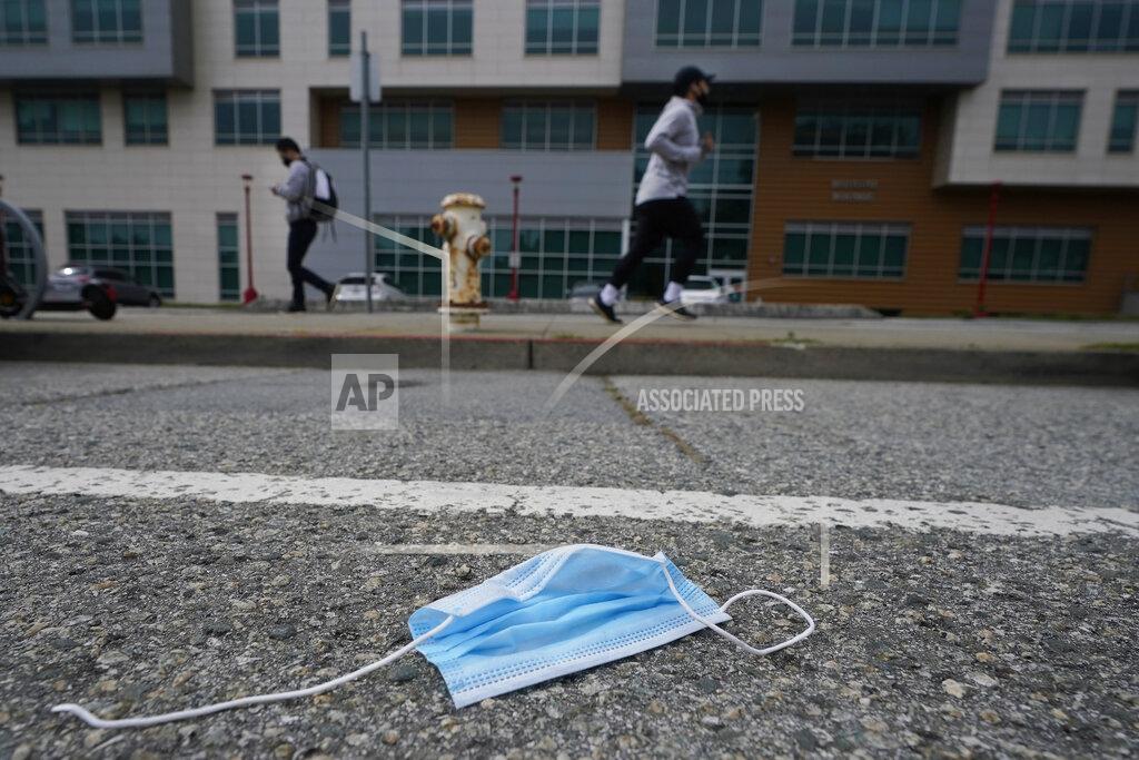 Jeff Chiu A discarded face mask lies in the street in San Francisco, Wednesday, March 17, 2021. Disposable masks, gloves and other personal protective equipment have safeguarded untold lives during the pandemic. They’re also creating a worldwide environmental problem, littering streets and sending an influx of harmful plastic into landfills and oceans. (AP Photo/Jeff Chiu)