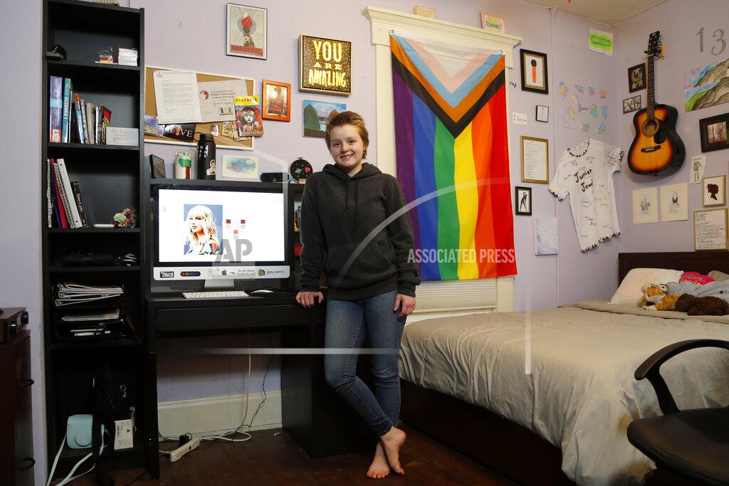 Jay Laprete Graciela Leahy, 13, an eighth grader at Ohio's Columbus Gifted Academy, stands next to her computer in her bedroom, in Columbus, Ohio, Feb. 23, 2021, to begin a stretch of nearly six straight hours at her desk. A year later in the pandemic, the unplanned experiment with distance learning continues for thousands of students like Leahy who have yet to set foot back in classrooms. (AP Photo/Jay LaPrete)